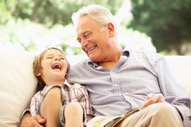 Grandfather With Grandson Reading Together On Sofa